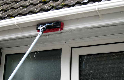 A white UPVC fascia board being brushed clean