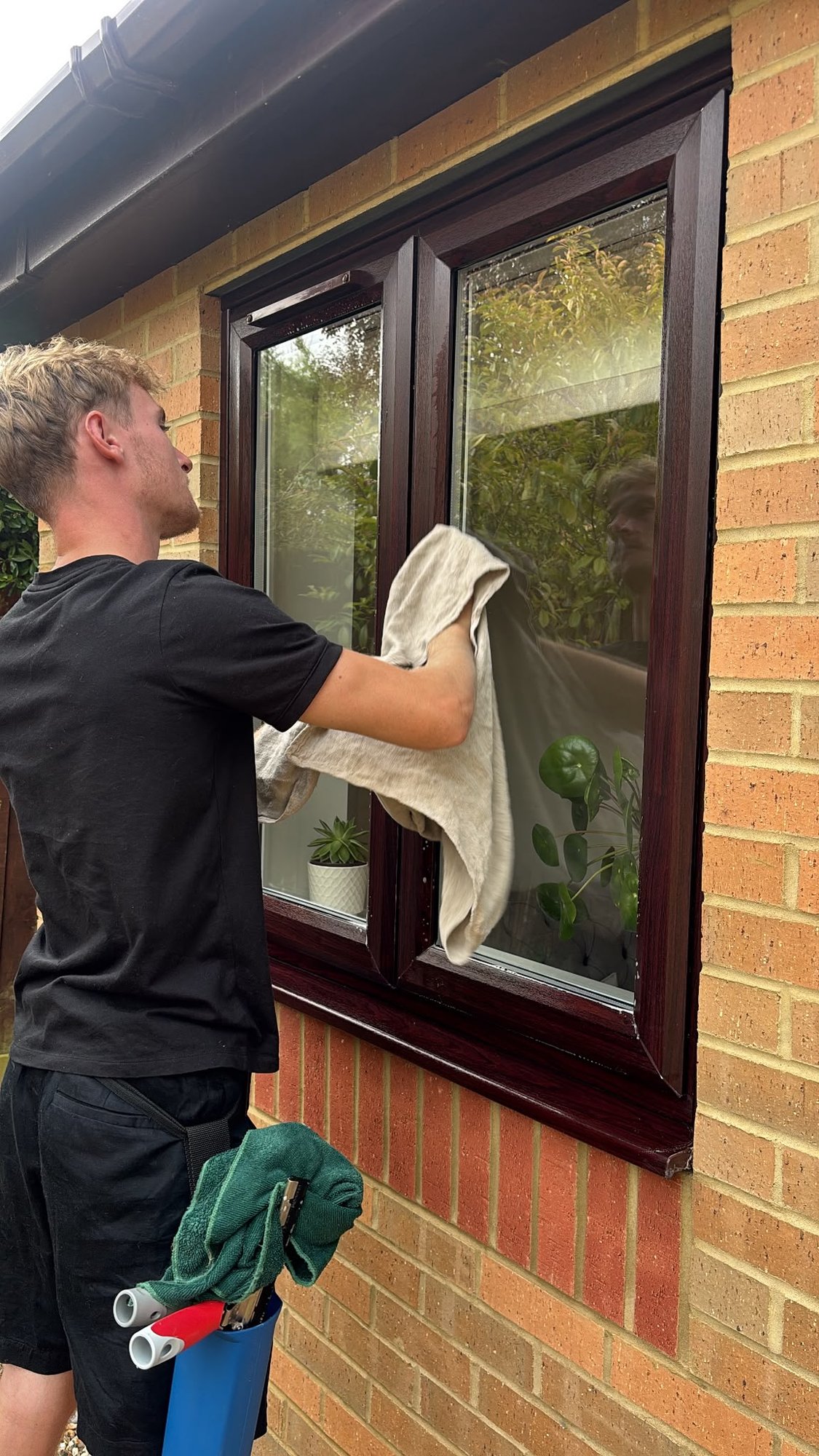 Window being dried by hand with a scrim cloth